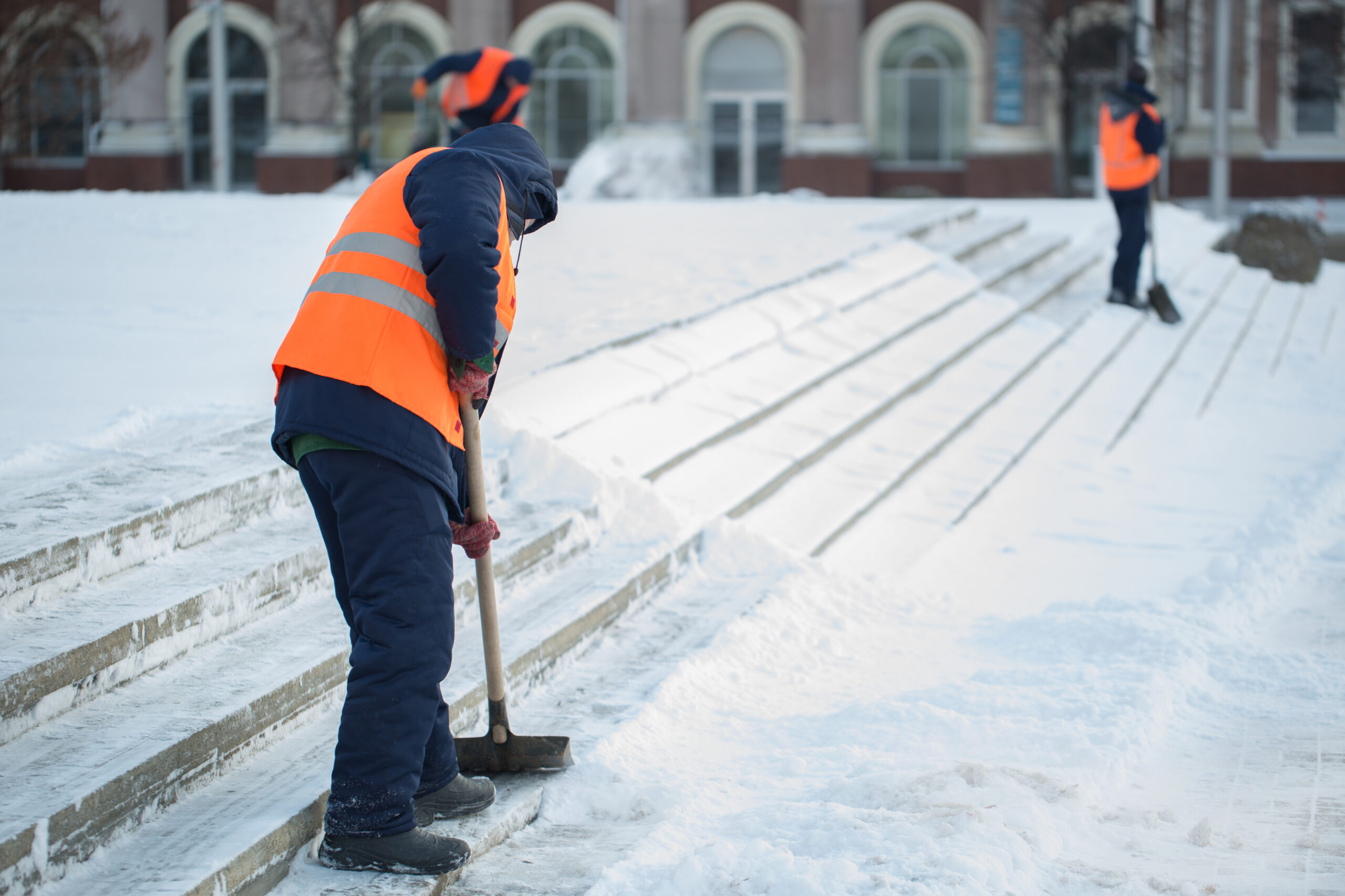Workers sweep snow from road in winter, Cleaning road from snow storm.