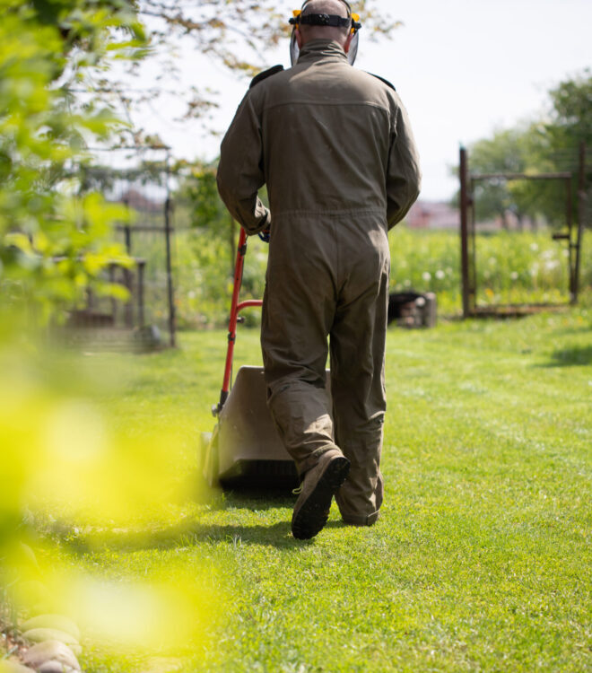 Mowing the grass with a lawn mower. Garden work concept background.